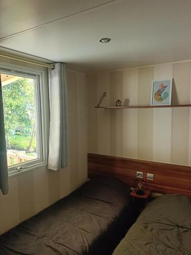 une petite pièce avec un lit et une fenêtre dans l'établissement Mobil Home climatisé 3 chambres - Parc des 7 fonts, à Agde
