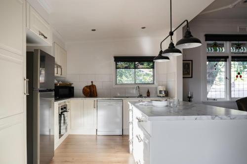 a kitchen with white cabinets and a counter top at Poets Corner vintage retreat walk to View St in Bendigo
