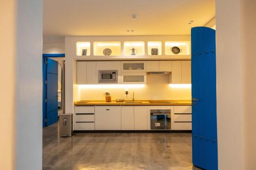 a kitchen with white cabinets and a blue door at شاليهات مايرون - Myron Chalets in Riyadh