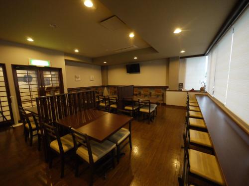 a dining room with tables and chairs and a bar at Hotel Route-Inn Court Kofu Isawa in Fuefuki