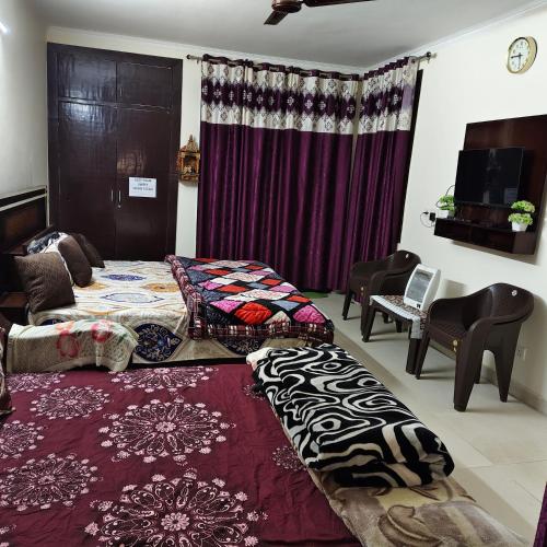 a room with two beds and a couch and a table at Nainital Cotteges in Rāmgarh