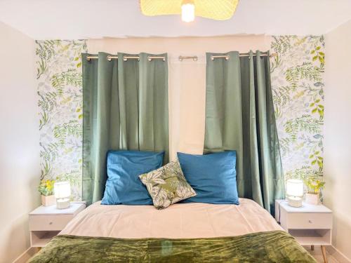 a bedroom with green curtains and a bed with blue pillows at Joli T2 avec wifi et Netflix proche du golf in Bellême