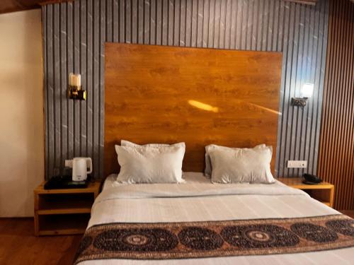 a bedroom with a large bed with a wooden headboard at Jubilant Farm House in Rishīkesh
