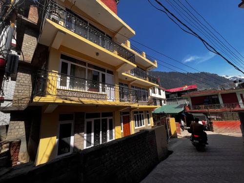 a yellow building with balconies and a person on a motorcycle at Jubilant Farm House in Rishīkesh