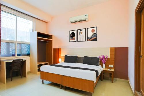 a bedroom with a bed and a desk and a window at Super Hotel O JLN Marg Malviya Nagar Formerly Hotel Braj Haveli in Jaipur