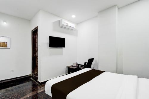a white bedroom with a bed and a tv at Super Hotel O Malkajgiri in Hyderabad