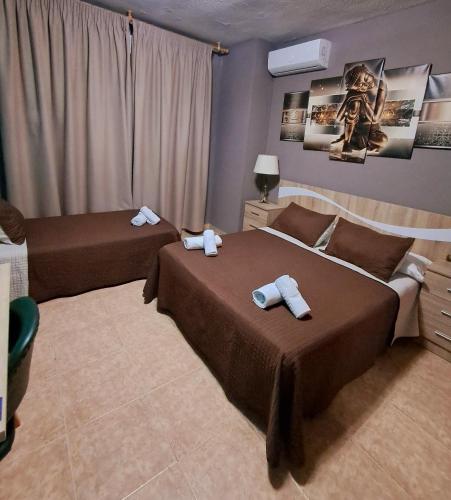 una camera da letto con due letti con asciugamani sopra di Hostal Doña María a Valdemoro