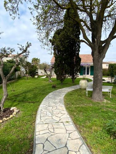 a walkway in a park with a bench and trees at Le chêne vert in Saintes-Maries-de-la-Mer