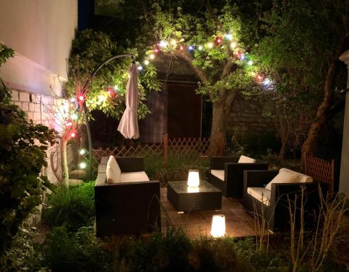 - un jardin avec des lumières, des chaises et un parasol dans l'établissement Issy Zen House Spa - Paris Expo - Porte de Versailles - Maison 140m2 - Proche Roland Garros, à Issy-les-Moulineaux