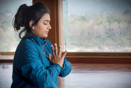 a woman holding a candle in front of a window at HOLYWATER Hotel by Ganga Kinare #150 mts from Ganga Ghat Rishikesh in Rishīkesh