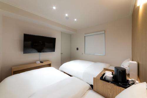 a hotel room with two beds and a flat screen tv at Bread Hill Hotel Jongno in Seoul