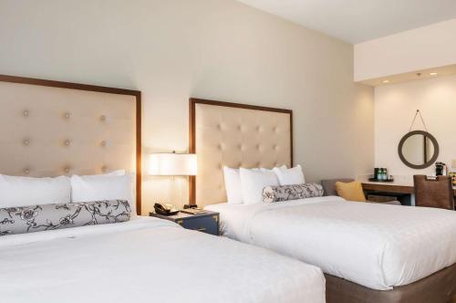 a hotel room with two beds and a desk at St Charles Coach House, an Ascend Collection Hotel in New Orleans