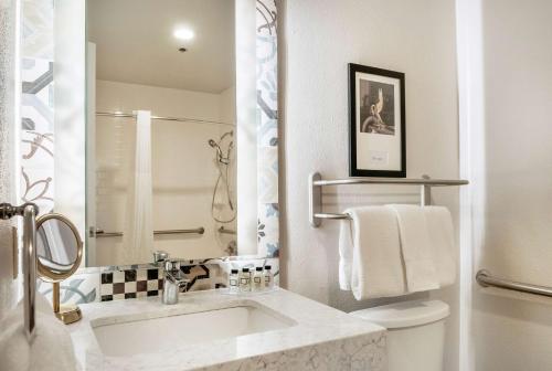 a white bathroom with a sink and a toilet at St Charles Coach House, an Ascend Collection Hotel in New Orleans