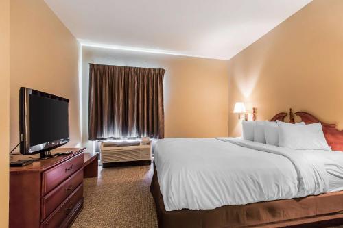 a hotel room with a bed and a flat screen tv at Quality Suites New Iberia in New Iberia