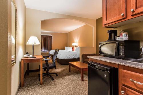 a small hotel room with a bed and a kitchen at Quality Suites New Iberia in New Iberia