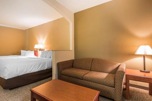 a hotel room with a bed and a chair at Quality Suites New Iberia in New Iberia