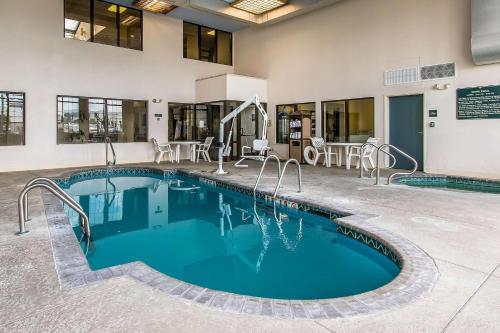 a swimming pool in a hotel with chairs and tables at Quality Suites New Iberia in New Iberia