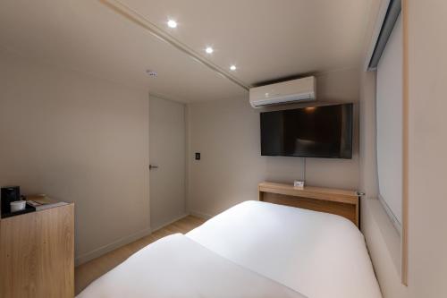 a bedroom with a bed and a flat screen tv at Bread Hill Hotel Jongno in Seoul