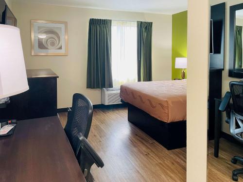 a small hotel room with a bed and a desk at Quality Inn & Suites Lake Charles South in Lake Charles