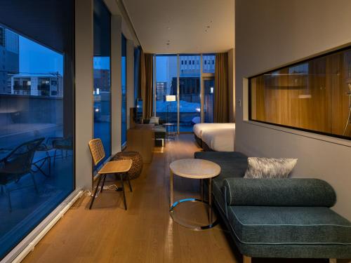 a hotel room with a couch and a table and chairs at SAPPORO HOTEL by GRANBELL in Sapporo