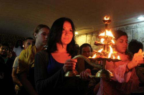 a woman holding a tray of lit candles at HOLYWATER Hotel by Ganga Kinare #150 mts from Ganga Ghat Rishikesh in Rishīkesh