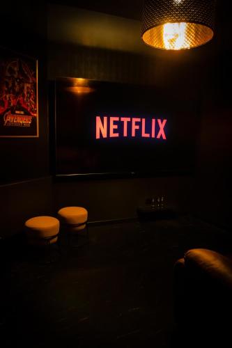 Deux tabourets dans une pièce sombre avec un panneau netflix dans l'établissement Suite 7 ème Art - CINE ROOM, Logement insolite - atypique, à Homécourt