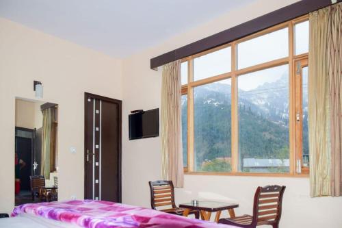 a bedroom with a table and chairs and a large window at Red Inn in Vashisht