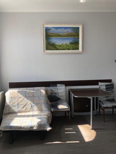 a room with a bed and a table and a painting at Готель Оазис in Chernivtsi