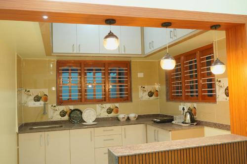 a large kitchen with white cabinets and windows at Athira Residency Coorg in Kushālnagar
