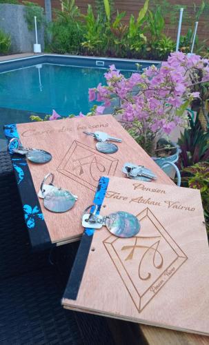 a wooden table with butterflies and scissors on it next to a pool at Fare Atihau Vairao in Matiti