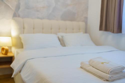 a white bed with two towels on top of it at Zlatiborske terase Spa&Wellness in Zlatibor