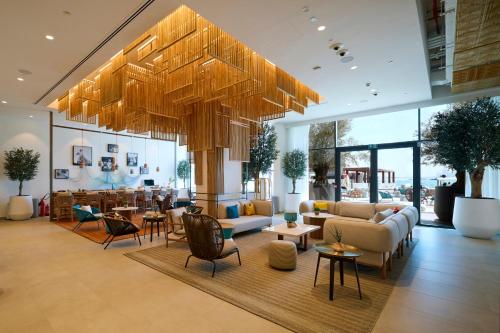 a lobby with couches and chairs and a table at Rove Al Marjan Island in Ras al Khaimah