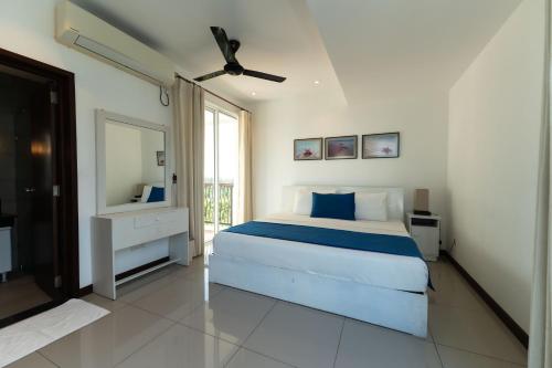 a white bedroom with a bed and a mirror at Oceanfront Condominium - Nilaveli in Nilaveli