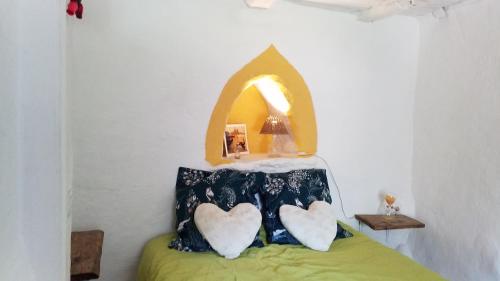 a bedroom with a bed with two heart pillows at Le MàS du Plot in Sablières