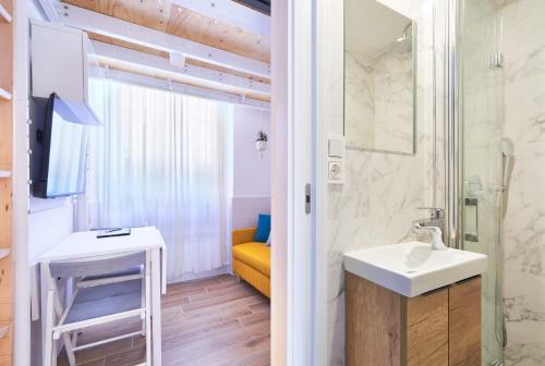 a bathroom with a sink and a mirror and a yellow chair at MalagaHomeStudio in Málaga