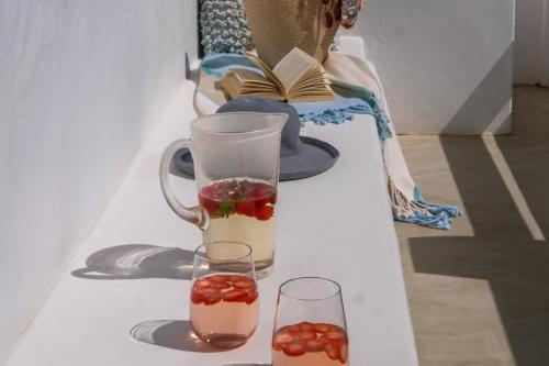 a table with two glasses and a vase with fruit in it at Dankbaar Holiday Home in Paternoster