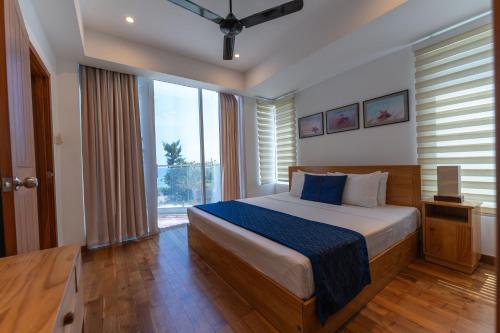 a bedroom with a bed and a large window at Oceanfront Condominium - Nilaveli in Nilaveli