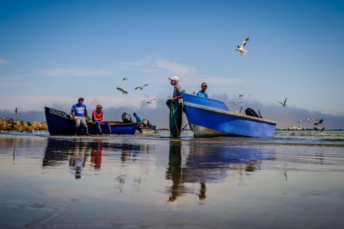 a group of people in boats on the beach at Dankbaar Holiday Home in Paternoster