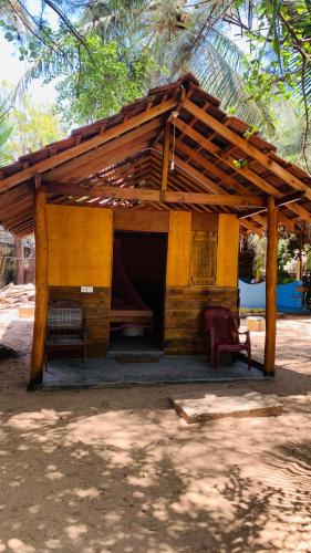 a small building with a wooden roof and a chair at Breezy Beach Cabanas in Arugam Bay