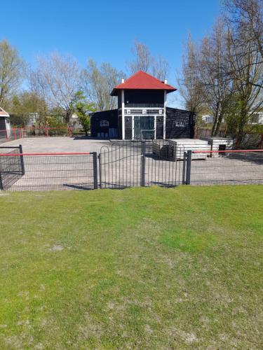 a fence in front of a park with a building at Chalet Makkum C99B met prive gelegen tuin aan het water in Makkum