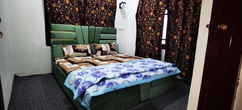 a bedroom with a bed with a green headboard at House of Fragrance in Srinagar