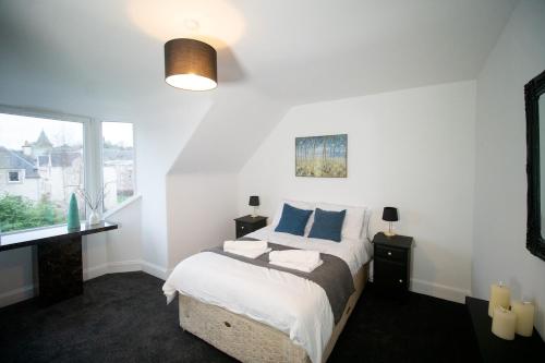 a bedroom with a bed with blue pillows and a window at Beautify Refurbished Large 3 Bed Terrace in Hawick