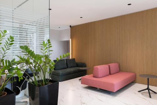 a living room with a pink chair and a couch at Energy Park Hotel in Vimercate