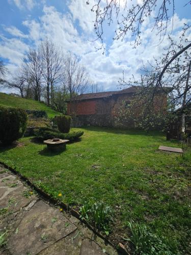 a grassy yard with a brick wall and a bench at Къща за гости Хитър Петър in Apriltsi