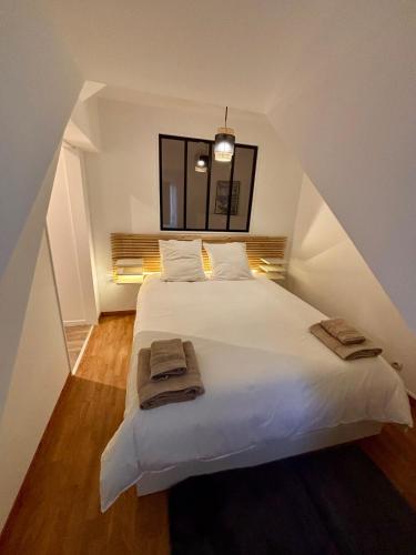 une chambre avec un grand lit blanc avec deux serviettes dessus dans l'établissement Maison en Triplex proche centre-ville, à Val de Saire