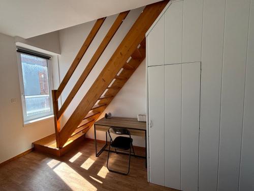 Cette chambre dispose d'un bureau et d'un escalier avec une chaise. dans l'établissement Maison en Triplex proche centre-ville, à Val de Saire