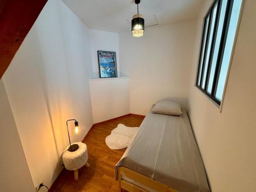Cette petite chambre comprend un lit et une lampe. dans l'établissement Maison en Triplex proche centre-ville, à Val de Saire