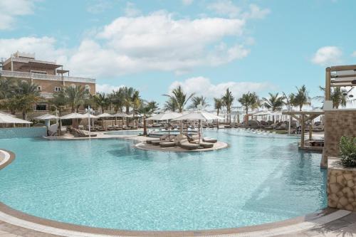 a swimming pool with chairs and umbrellas at a resort at Wyndham Residences The Palm in Dubai