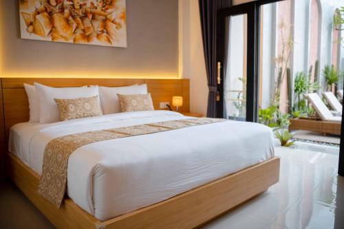 a bedroom with a large bed and a large window at La Tano's Canggu in Canggu