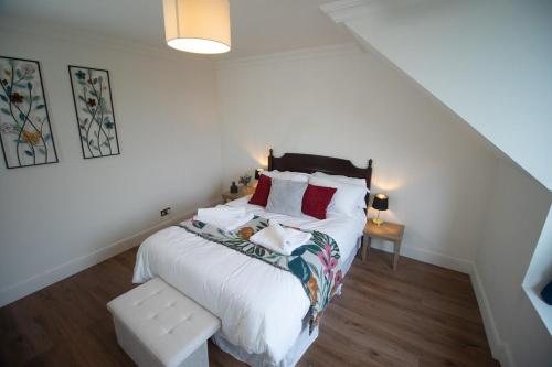 a white bedroom with a bed and a bench at Spacious 3 Bed Terrace with Large Kitchen Diner in Hawick